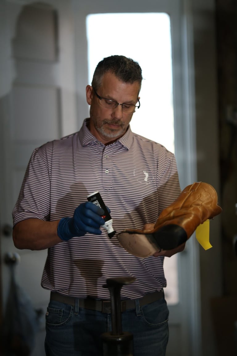 Man in striped shirt and glasses examining wooden object with gloved hands against bright background